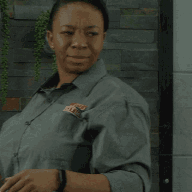 a woman wearing a gray shirt with a sticker on her chest that says ' gtc '