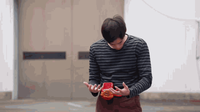 a man in a black and white striped shirt is holding a red object in his hands