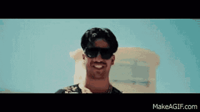 a man wearing sunglasses is smiling in front of a building