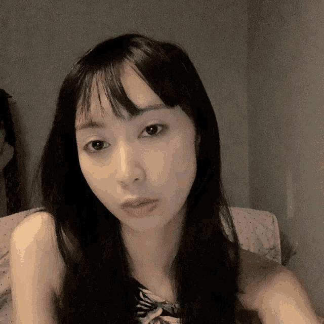 a woman with long black hair looks at the camera with a serious look on her face