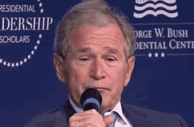 a man in a suit and tie is holding a microphone and making a face .