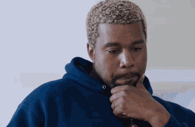 a man wearing a blue hoodie with a ring on his finger