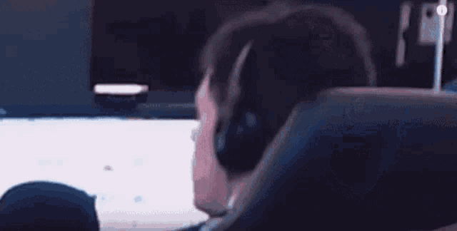 a man wearing headphones is asking what while sitting in front of a computer screen .