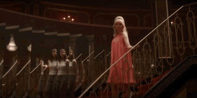 a woman in a red dress is walking down stairs