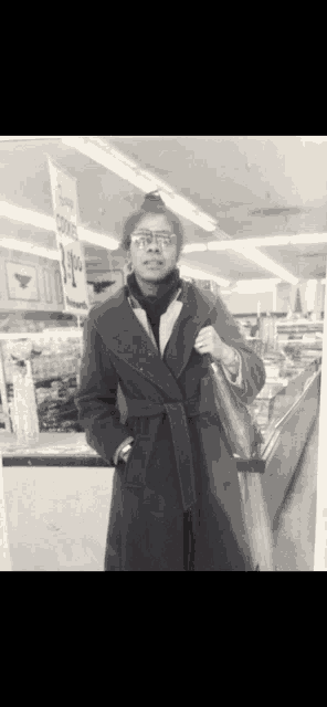 a black and white photo of a woman standing in a store