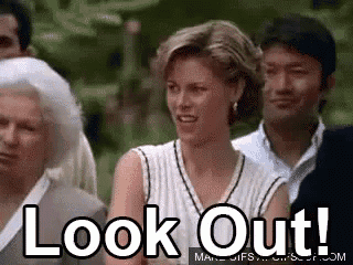 a woman is standing in a crowd of people with the words `` look out '' written on her face .