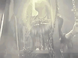 a woman is chained to a chair in a dark room with chains around her neck .
