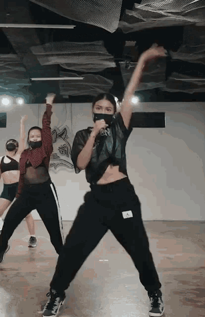 a woman wearing a mask is dancing in a room with other dancers