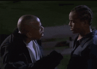 two men are standing next to each other and looking at each other in a dark room .