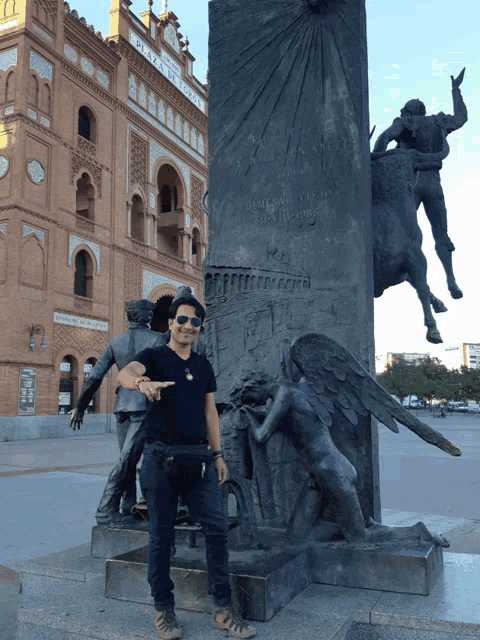 a man points at a statue in front of a building that says " plaza de toros "