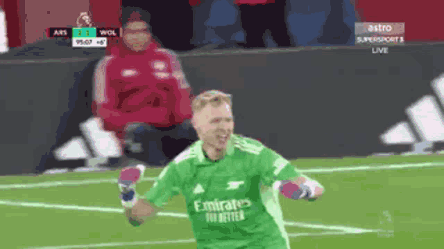 a soccer player wearing a green emirates jersey celebrates a goal