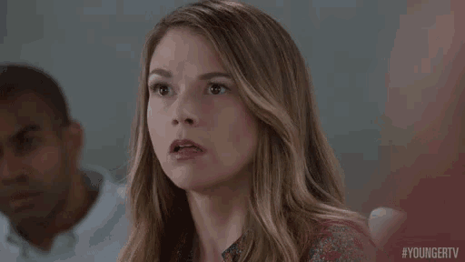 a woman is making a surprised face while sitting in front of a man .