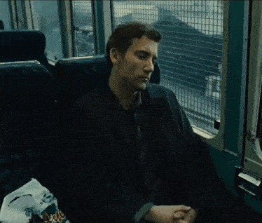 a man in a suit and tie is sitting on a bus looking out the window
