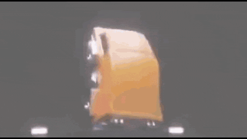 a yellow dump truck is driving down a dark road in the dark .