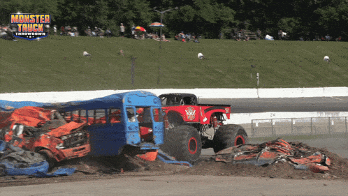 a monster truck is on a race track with a blue bus in the background