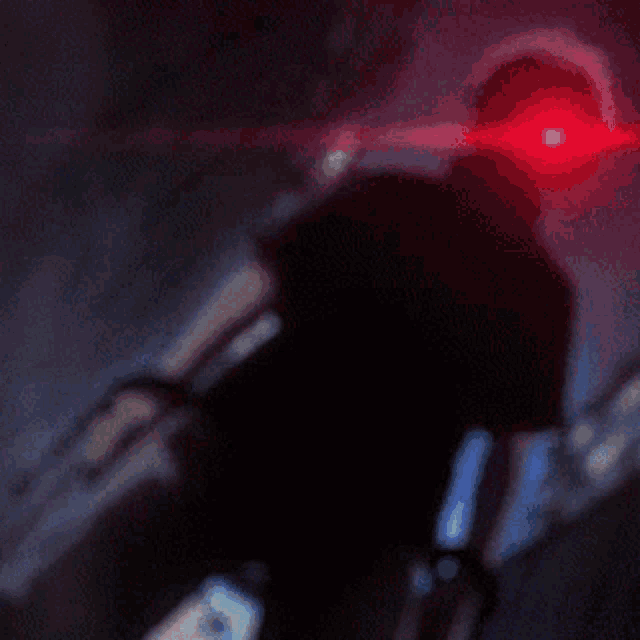 a person with red eyes is holding a sword in a dark room .