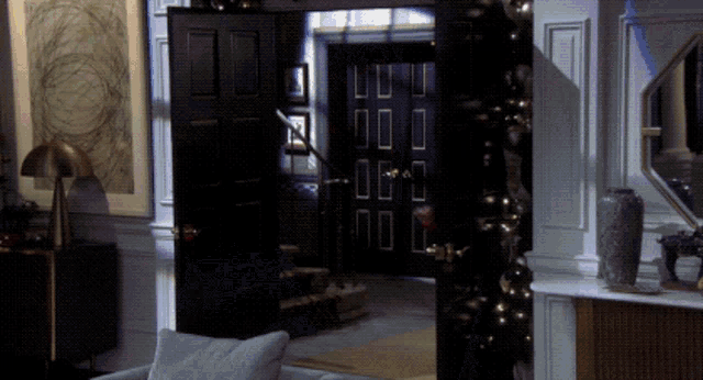 a living room with a black door and a staircase leading up to it
