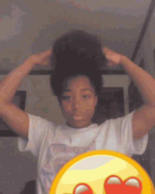 a girl in a white t-shirt is holding her hair up