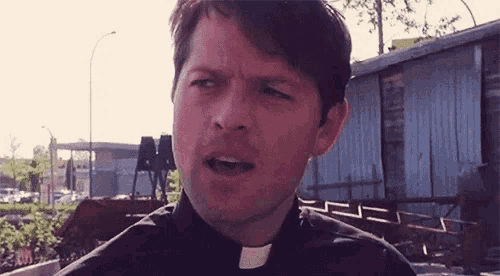 a man in a black shirt with a white collar is making a face