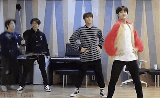 a group of young men are standing next to each other in a room and dancing .