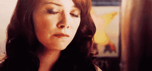 a close up of a woman 's face with her eyes closed and a painting in the background .