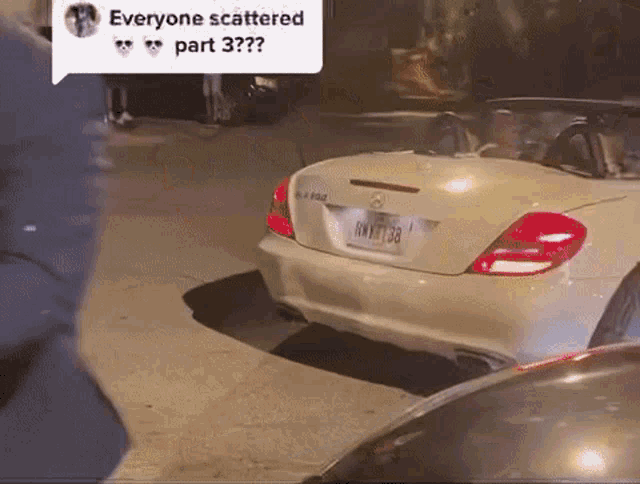 a white mercedes convertible is parked on the side of the road at night