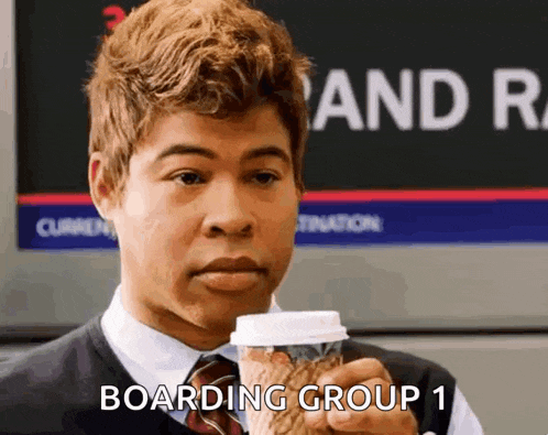 a man in a suit and tie is holding a cup of coffee and saying boarding group 1