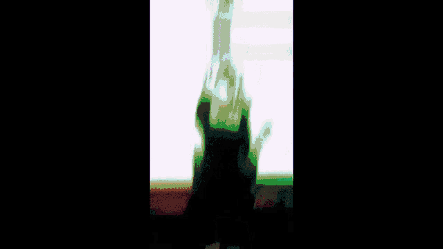 a blurry picture of a person holding a pink object in front of a window .