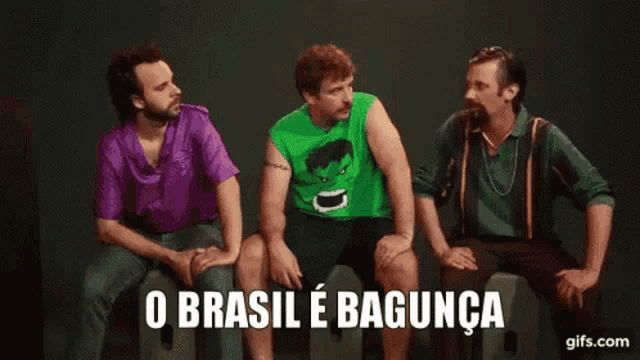 three men are sitting next to each other and one of them is wearing a green shirt with the hulk on it .