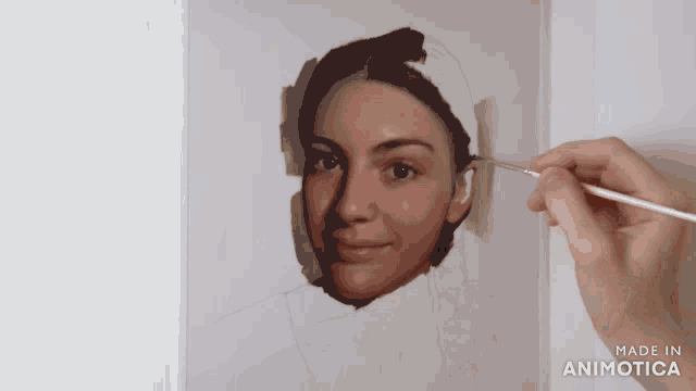 a person is painting a woman 's face with the words made in animotica behind them