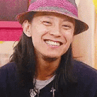 a man with long hair wearing a hat is smiling .