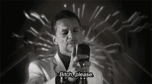a man in a white suit is holding a cell phone and says " bitch please "