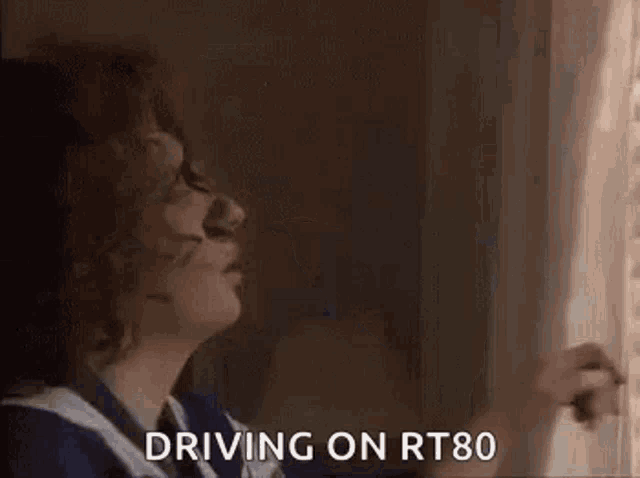 a woman is driving on rt80 and looking out the window .