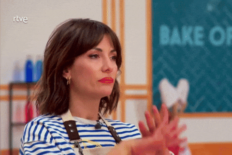 a woman in a striped shirt is clapping in front of a sign that says bake off