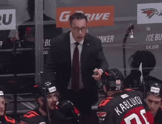 a man in a suit and tie is talking to a hockey player with the number 29 on his back