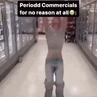 a man is standing in a hallway in a store with his arms up in the air .