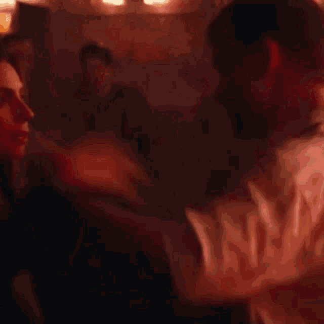 a blurry picture of a man and woman hugging in a dark room .