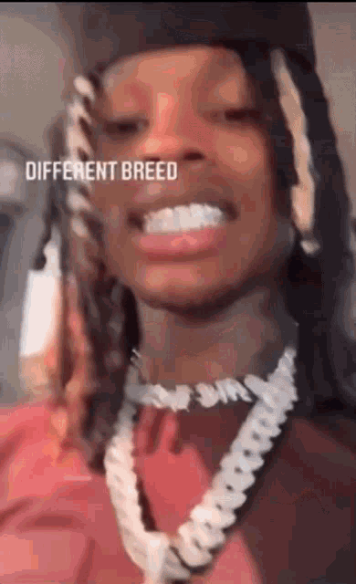 a man wearing a hat and a necklace with the words different breed written on his face .