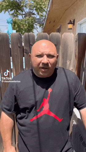 a bald man wearing a black air jordan t-shirt