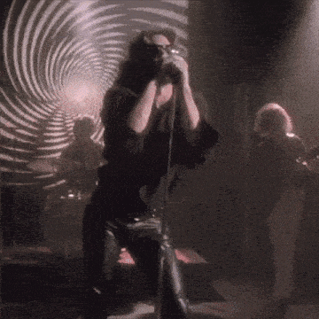a man singing into a microphone in front of a striped wall