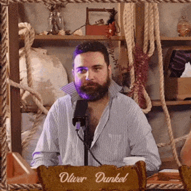 a man with a beard and a sign that says oliver dunkel on it
