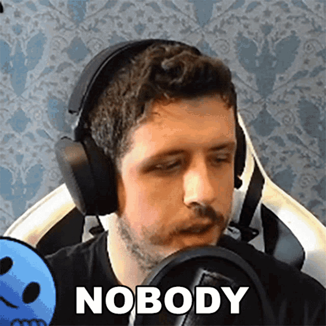 a man wearing headphones says nobody in front of a blue skull