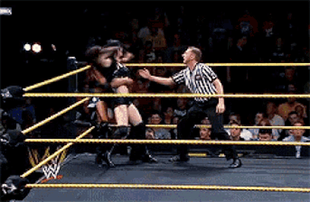 a referee stands in a wrestling ring with a woman in the middle
