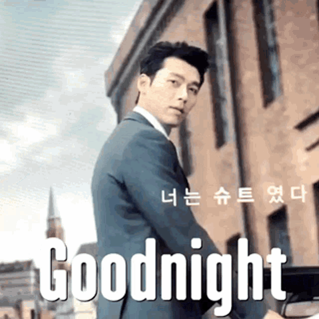 a man in a suit is standing in front of a building with the words goodnight in white letters .