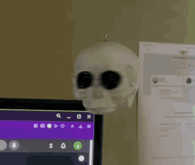 a skull is sitting on a desk next to a computer