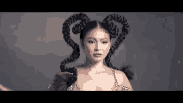 a woman with a very long braided hairstyle is standing in front of a gray wall .