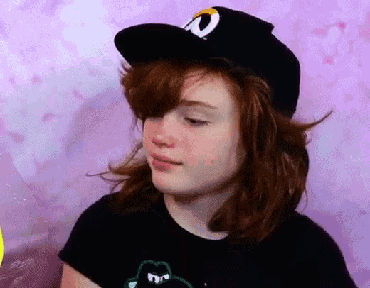 a young girl wearing a black hat and a black shirt with a frog on it