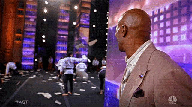 a man in a suit stands in front of a screen that says #agt on it