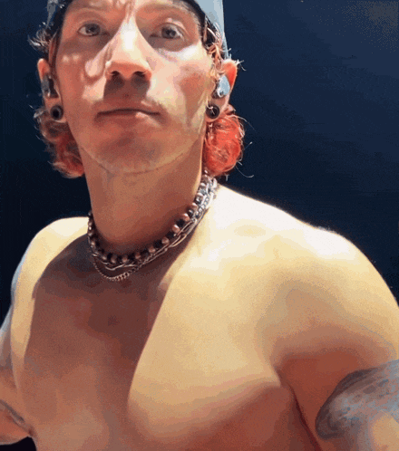 a shirtless man is wearing a hat and a necklace