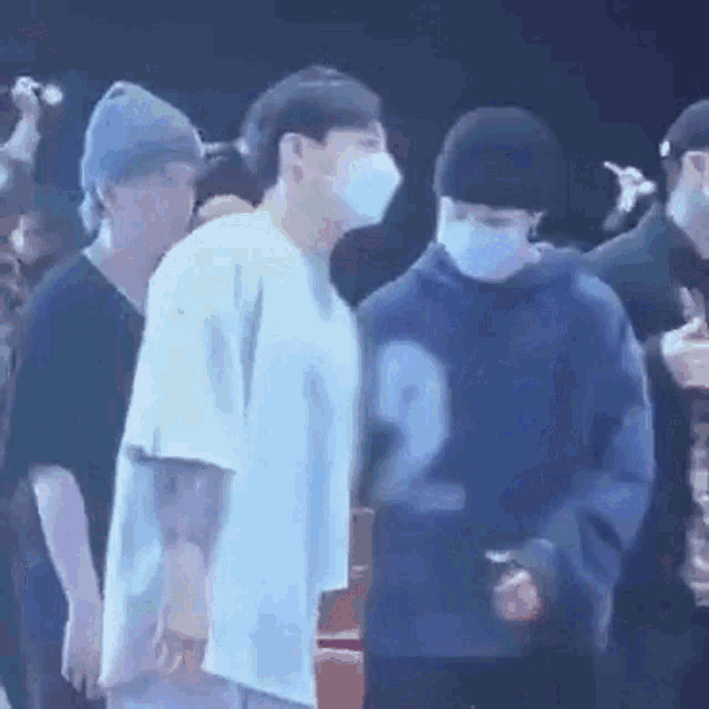 a group of men wearing masks are standing next to each other in a crowd .